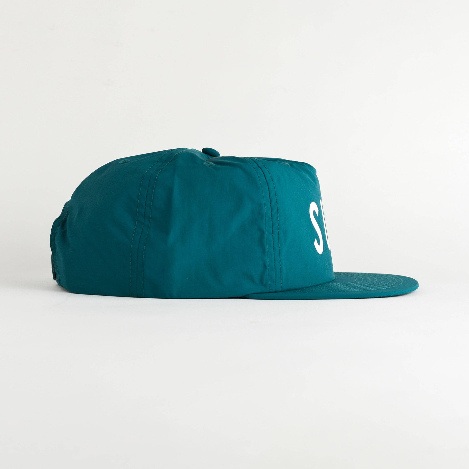 A teal 5-panel snapback cap with a white embroidered 'S' on the side, shown from a side profile against a clean white background.