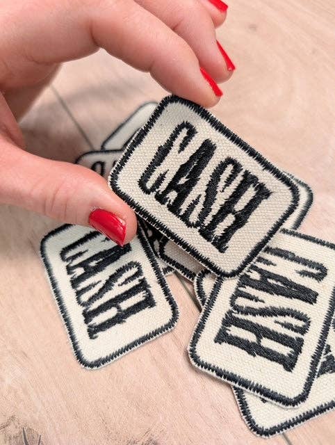 Hand holding multiple 'CASH' patches on a light background