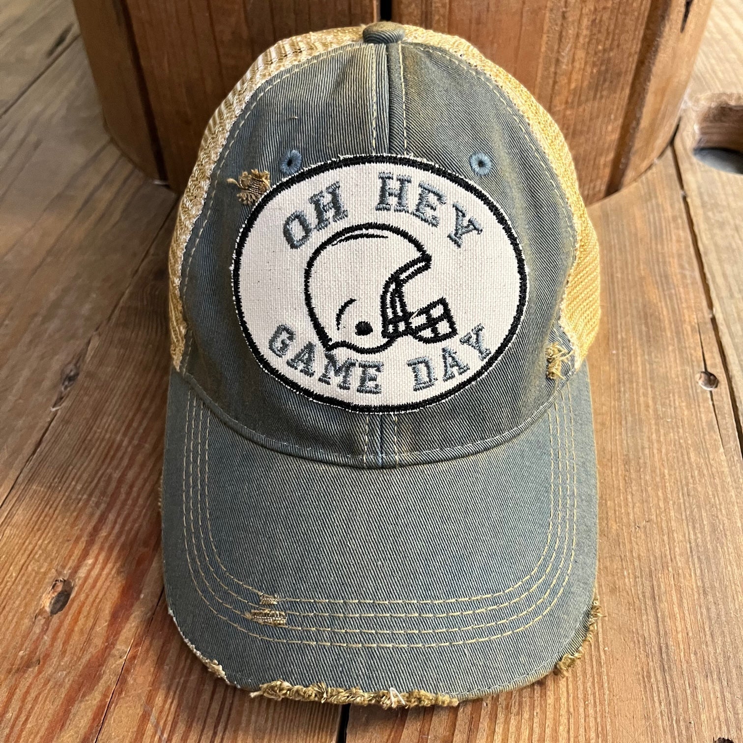 Vintage-style cap with 'Oh Hey Game Day' logo on a wooden surface