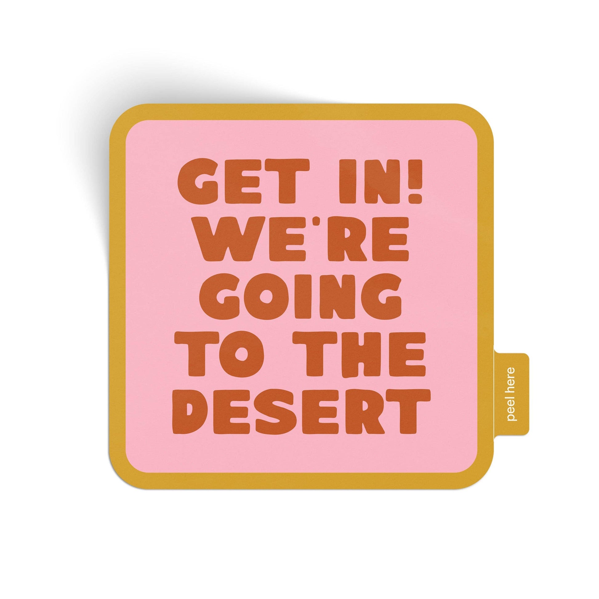 A square pink sticker with rounded corners, featuring the text 'GET IN! WE'RE GOING TO THE DESERT' in orange-brown block letters. The sticker has a mustard yellow border and a small side tab printed with 'peel here'.