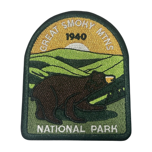 An embroidered patch for Great Smoky Mountains National Park, featuring a brown bear in the foreground, green hills, a yellow sky with 'GREAT SMOKY MTNS 1940' text, and 'NATIONAL PARK' at the bottom.