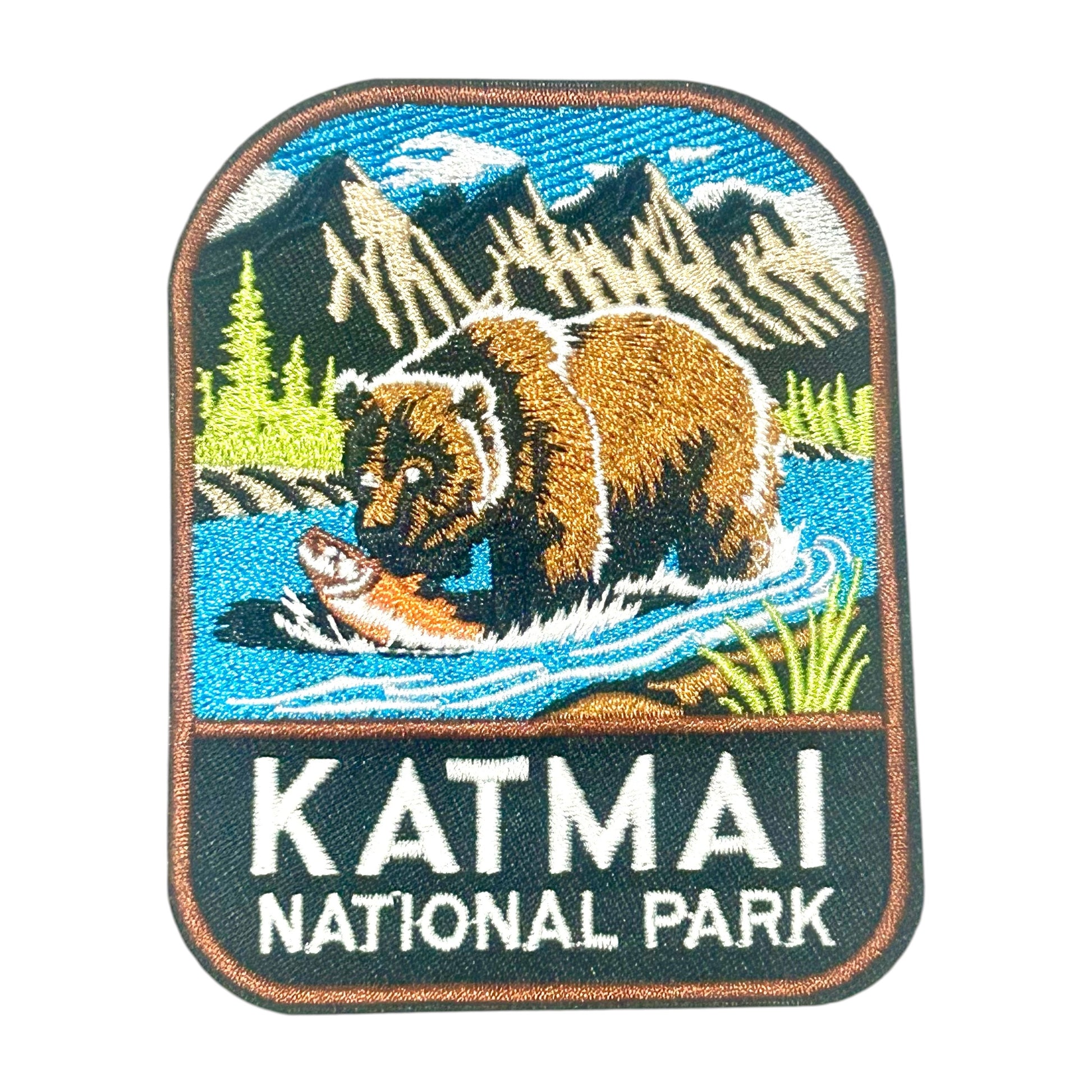 An embroidered patch featuring a brown bear catching a fish in a blue river, with mountains and trees in the background and the text 'KATMAI NATIONAL PARK' below.