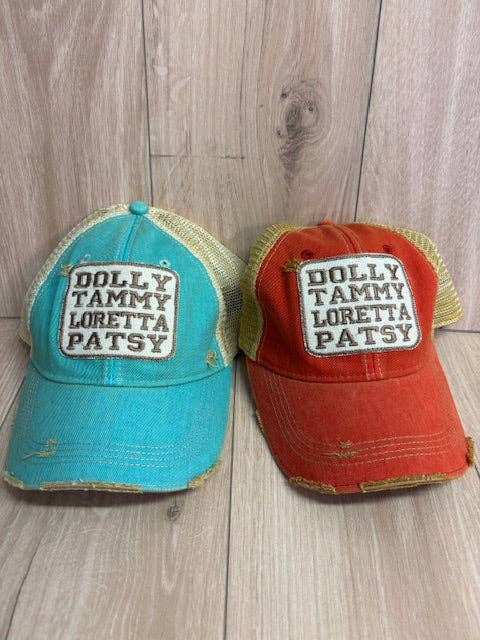 Two baseball caps with embroidered names Dolly Tammy Patsy Loretta on a wooden surface