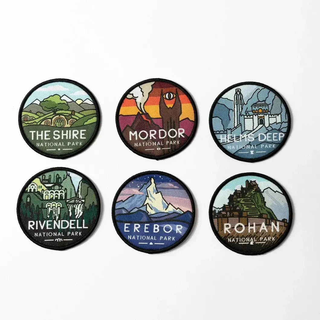 Set of six circular patches from Lord of the Rings with various locations and text on a white background. Shire National Park; Mordor National Park; Helms Deep; Rivendell National Park; Erebor; Rohan