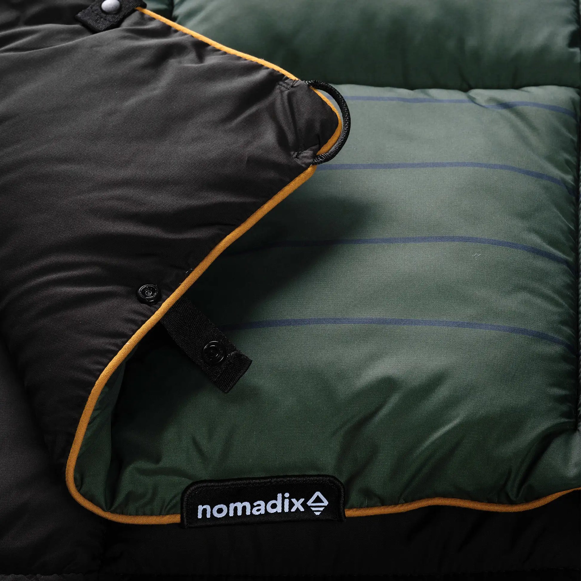 Green and black quilt with 'nomadix' logo on a dark background