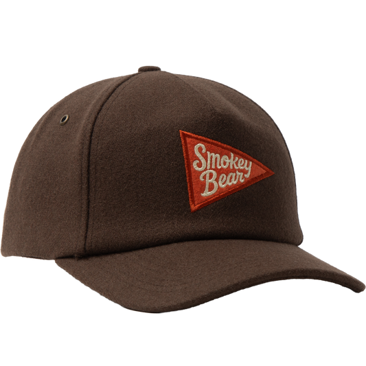 A dark brown wool-textured baseball cap featuring a red embroidered triangular patch on the front with the words 'Smokey Bear' in white script.