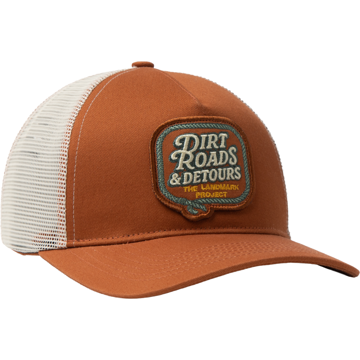 A brown and white trucker hat with a mesh back, featuring a brown embroidered patch on the front that reads 'Dirt Roads & Detours The Landmark Project'.