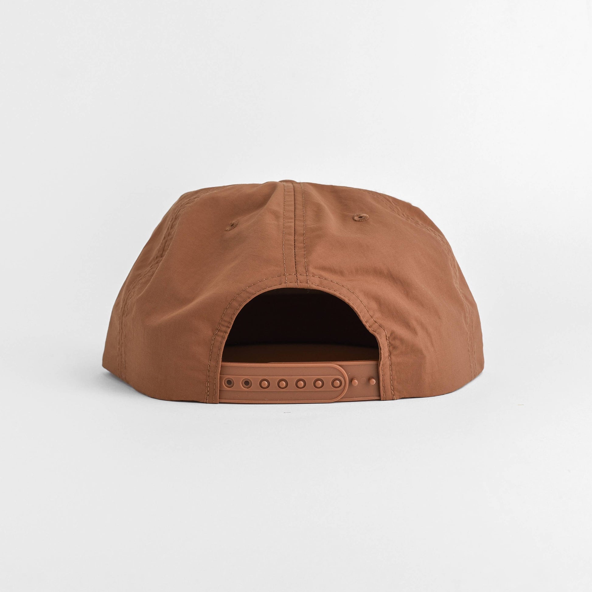 A brown snapback cap shown from the back, featuring a curved crown and adjustable strap with eyelets, photographed on a clean white background.