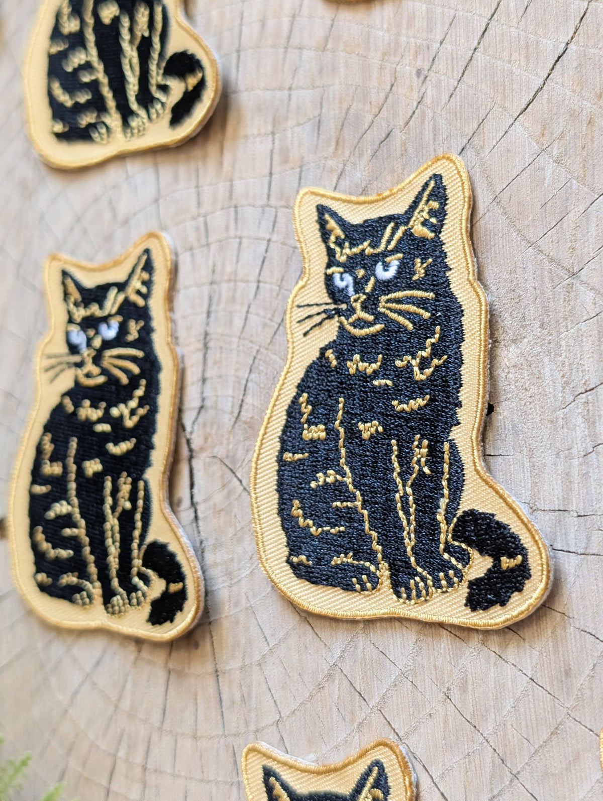 Embroidered cat patches on a wooden surface