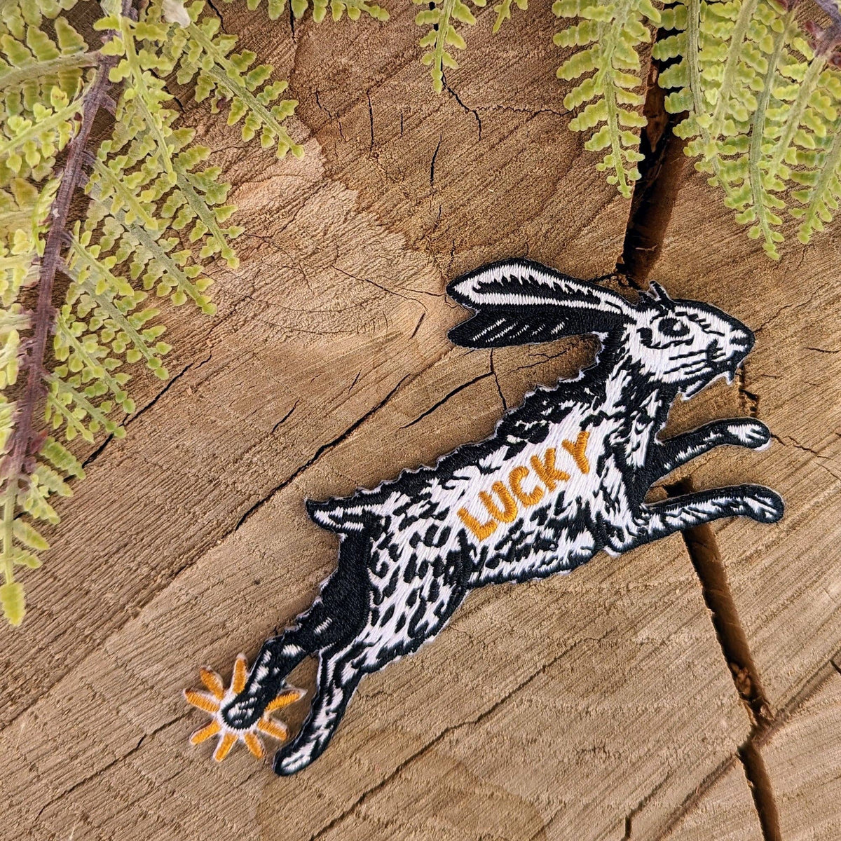 Embroidered patch of a rabbit with 'LUCKY' on a wooden background
