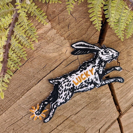 Embroidered patch of a rabbit with 'LUCKY' on a wooden background