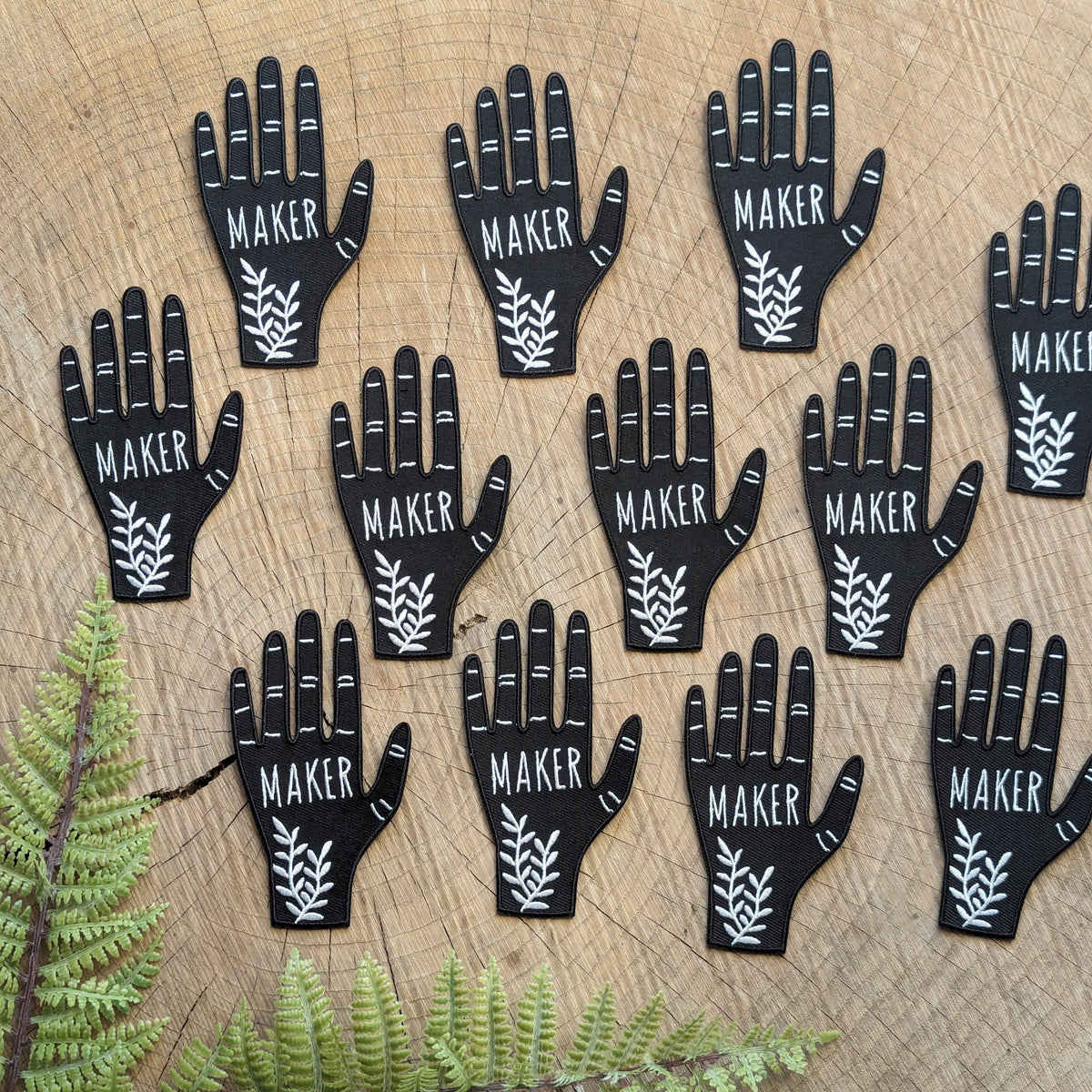 patch with 'MAKER' text on a wooden surface with ferns.