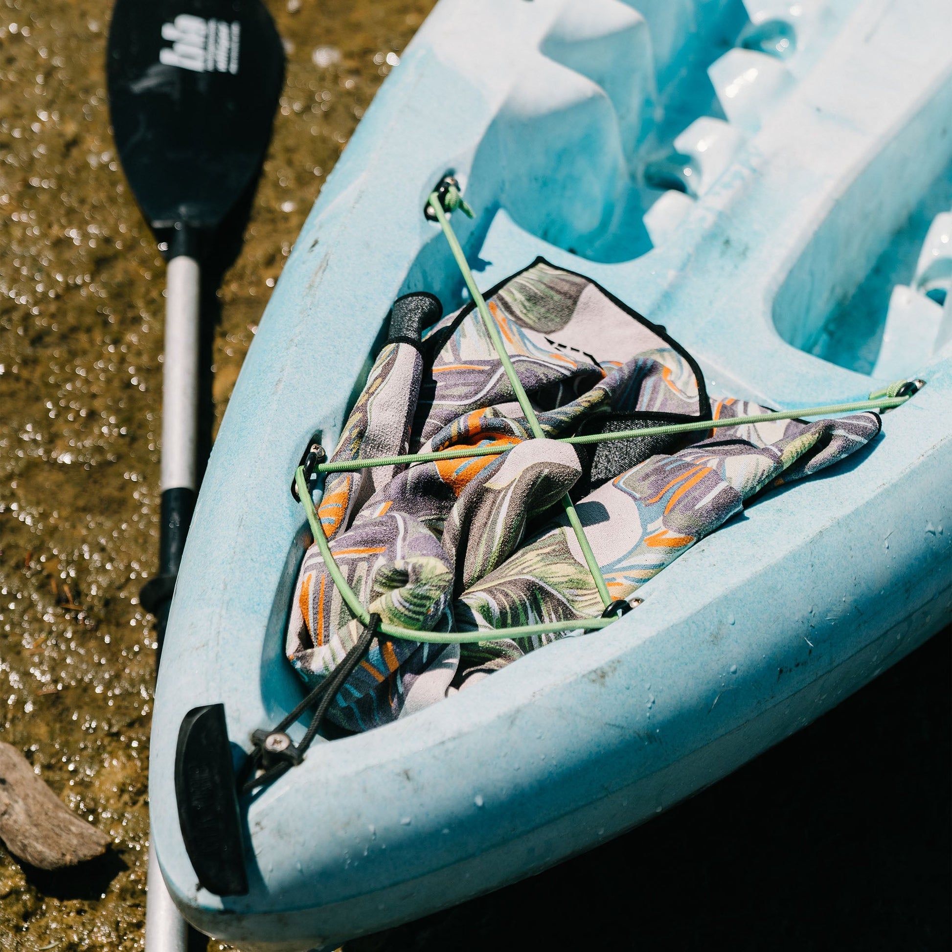 Blue kayak with a paddle and camouflage bag on a natural background