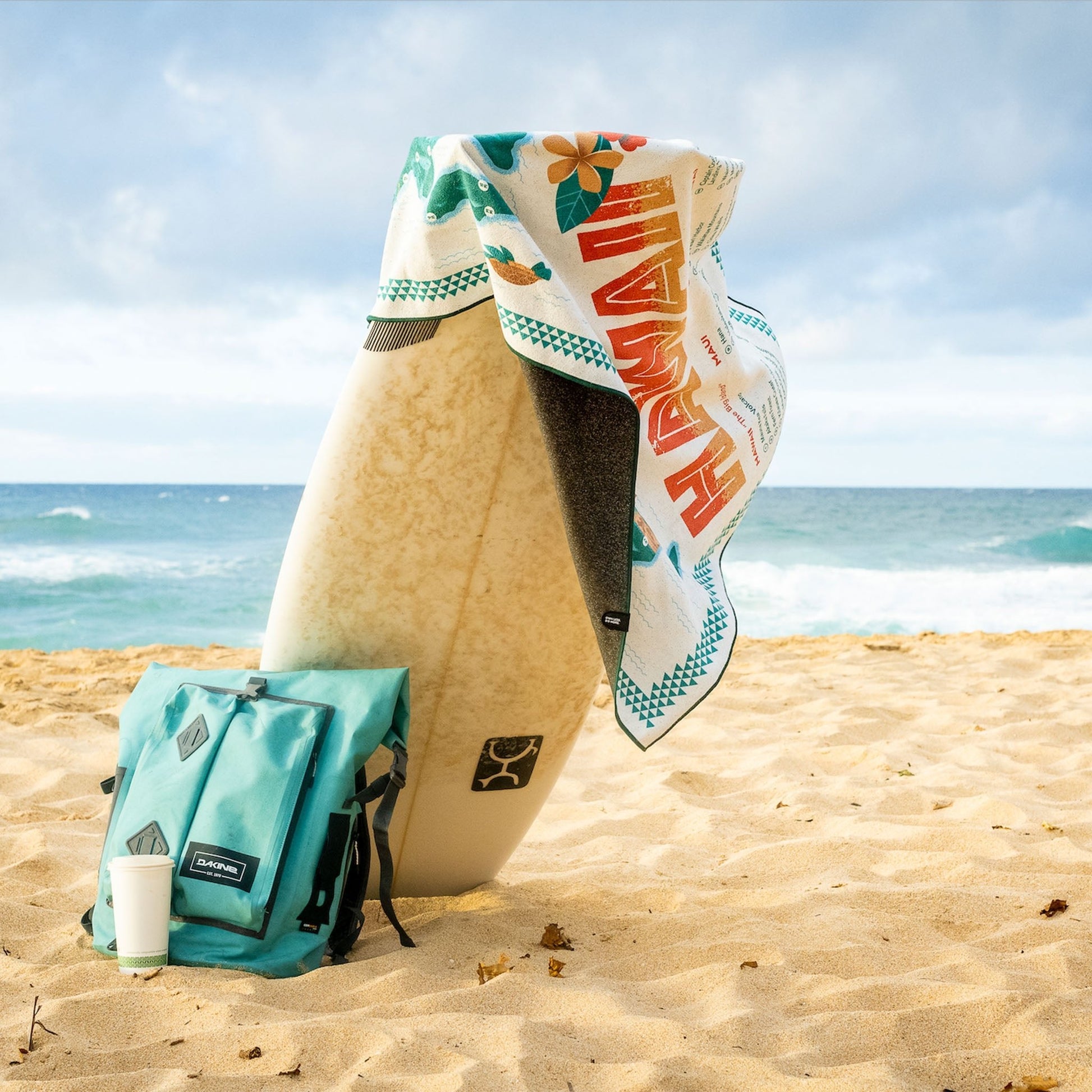 Surfboard with towel and bag on a sandy beach