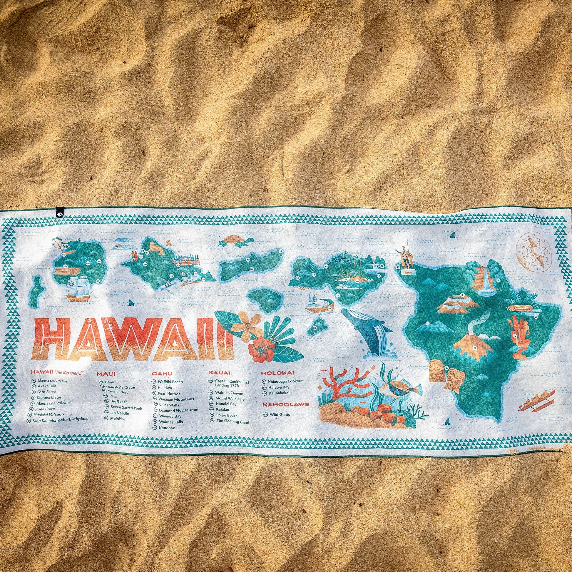 Hawaiian-themed towel with map design on sand