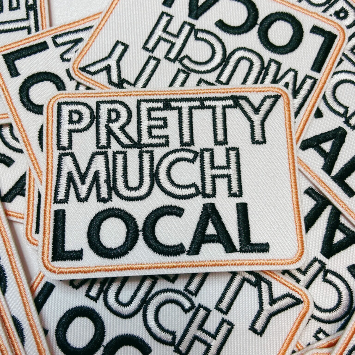 Embroidered patch with 'Pretty Much Local' text on a patterned background