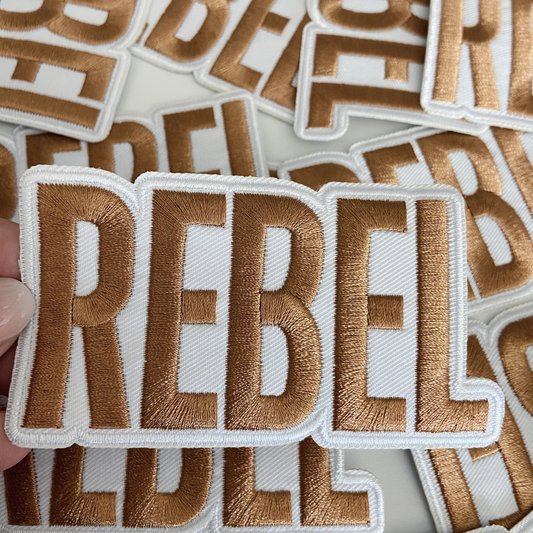 Embroidered patch with 'REBELS' text held by a hand, surrounded by more patches.