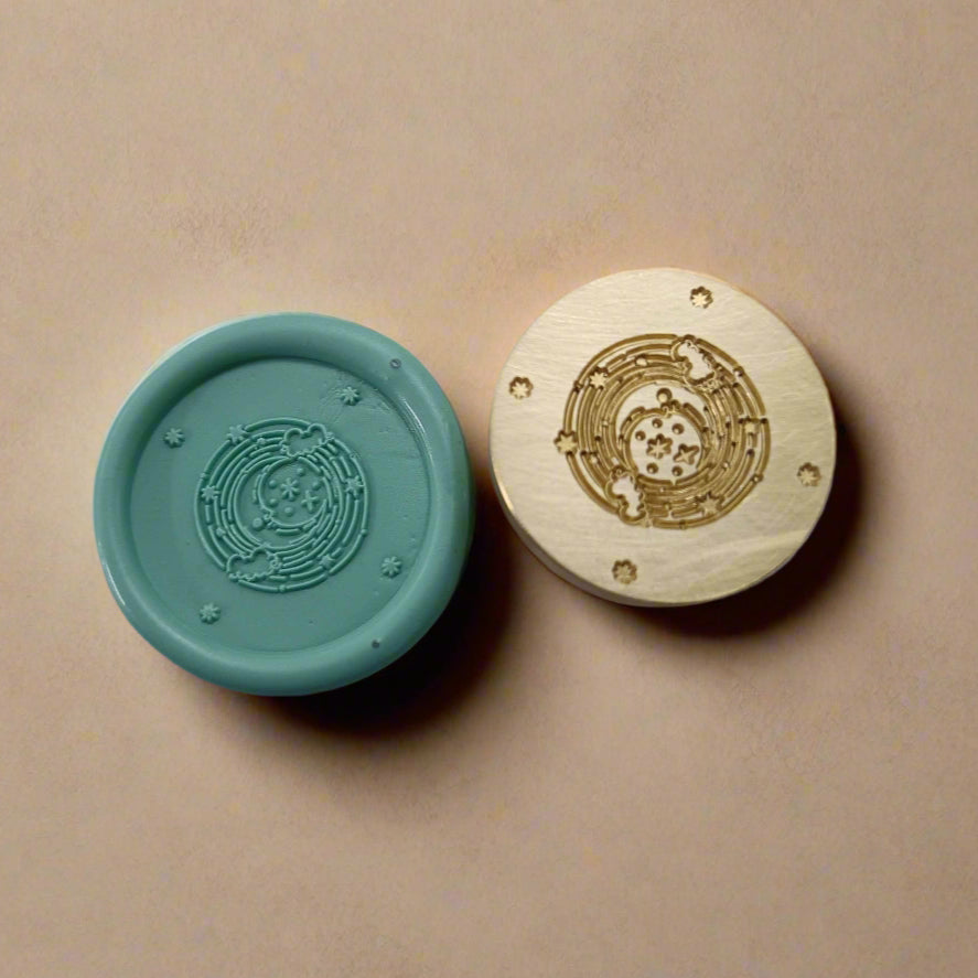 Two round objects, one teal and one gold, with intricate designs on a beige background